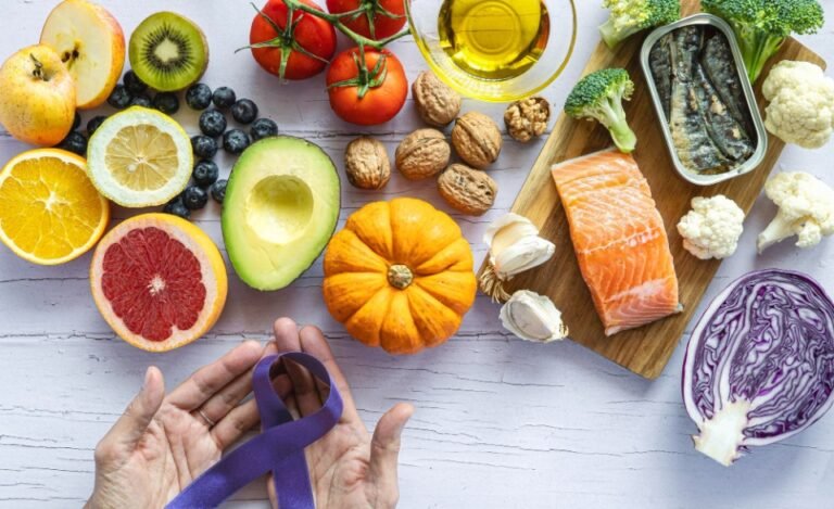 A variety of healthy foods like fruits, vegetables, salmon, nuts, and a purple cancer awareness ribbon.